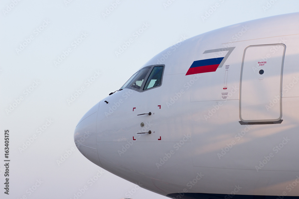 The nose of the aircraft in the light of the sunset with the Russian flag, the view from the side to the pilot's seat and the emergency exit door The nose of the aircraft in the light of the sunset with the Russian flag, the view from the side to the pilot's seat and the emergency exit door