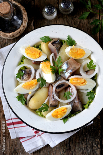 Salad from light-salted herring, boiled potatoes, eggs and onions with olive oil and lemon juice. Rustic style.