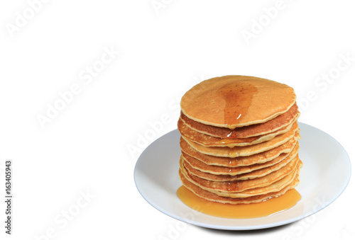 Stack of fresh made pancakes with maple syrup served on white plate, white background with free space for text and design 