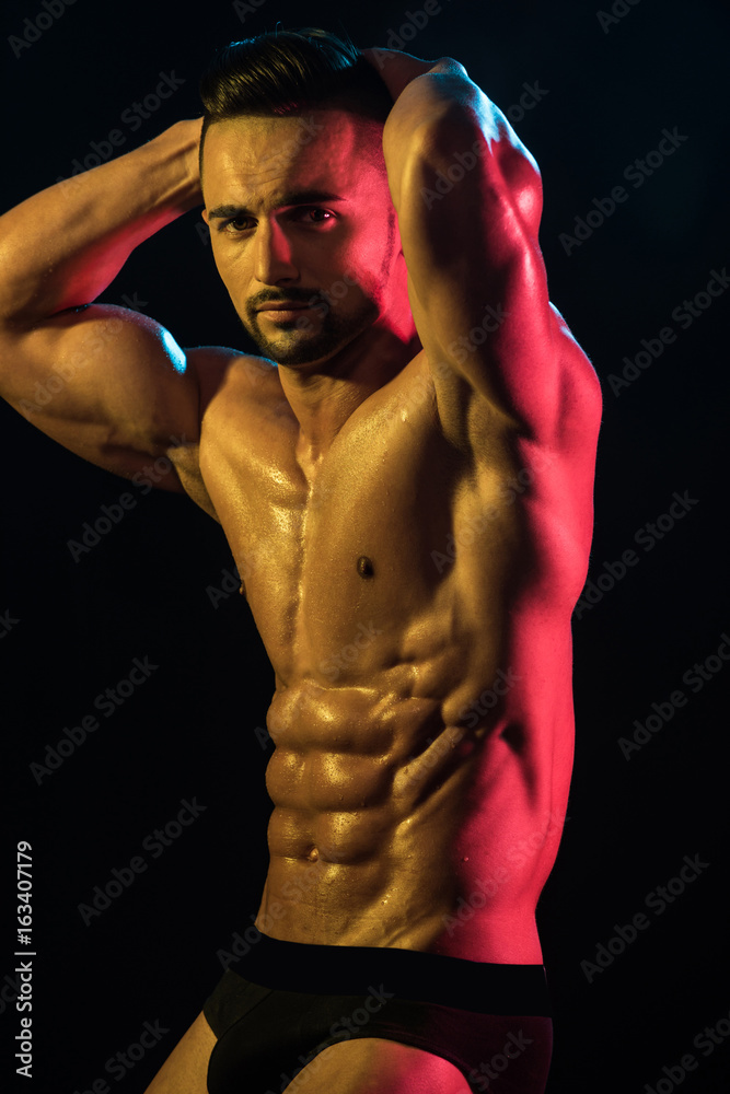 Strong Athletic Man Fitness Model Torso showing six pack abs on black  background. Sexy male muscular
