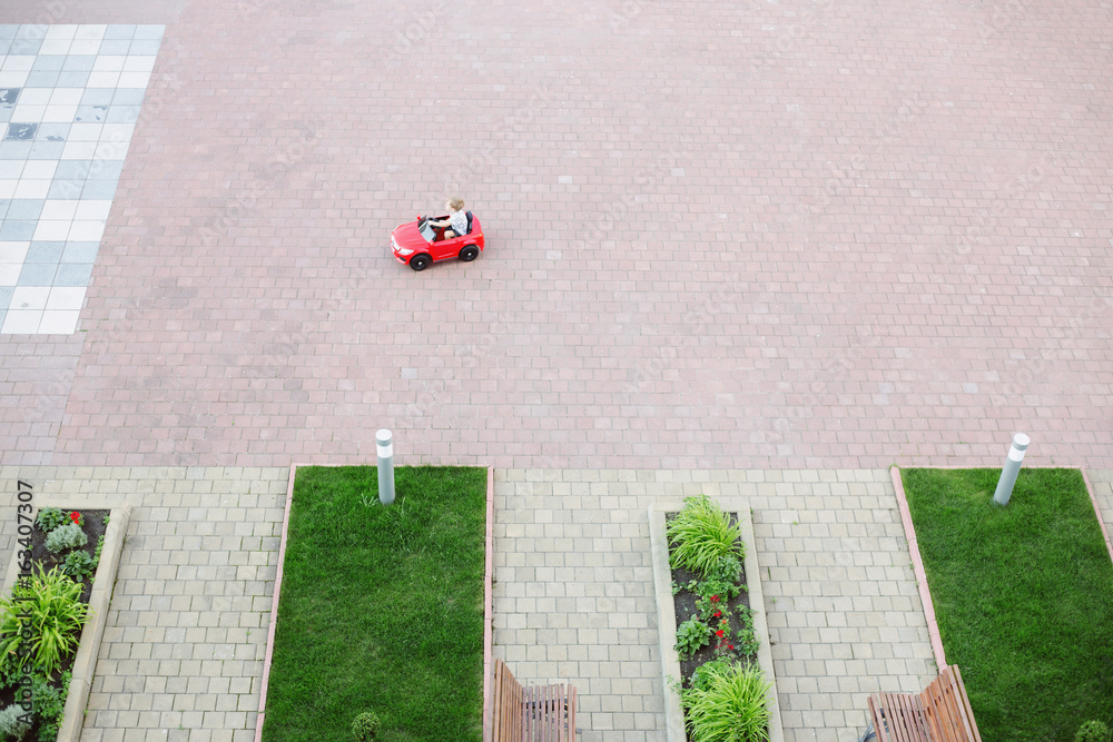 Obraz premium Top view of the toy red car for children in the yard