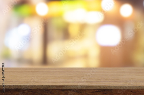 Perspective wooden table on top over blur coffee shop background, can be used mock up for montage products display or design layout.