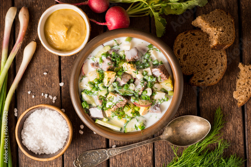 Okroshka. Traditional Russian summer cold yogurt soup in bowl on wooden background.