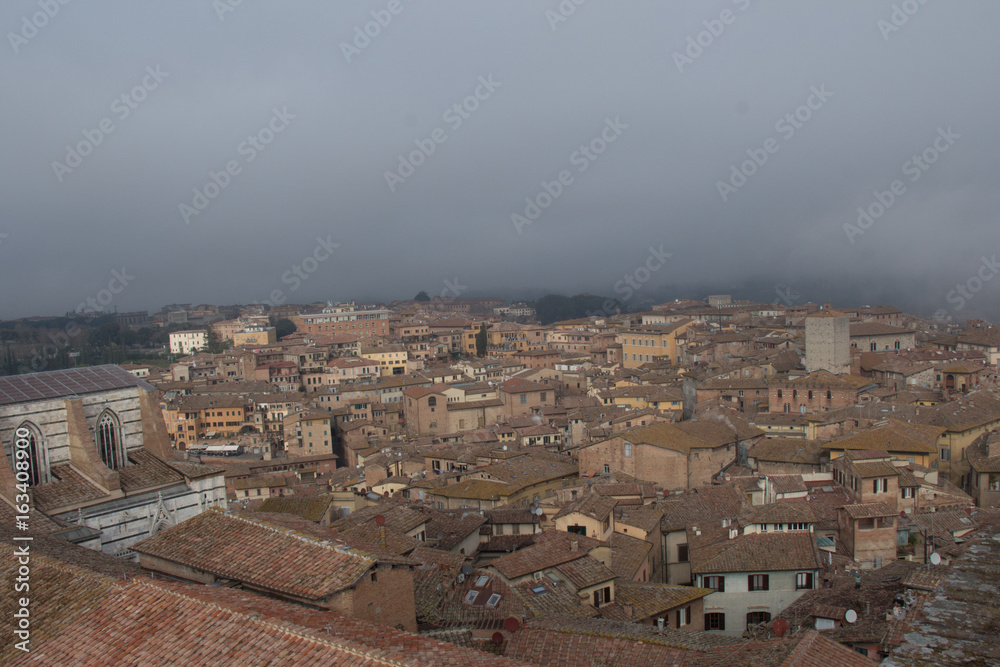 Cityscape of Siena with thick fog on background. Tuscany, Italy.