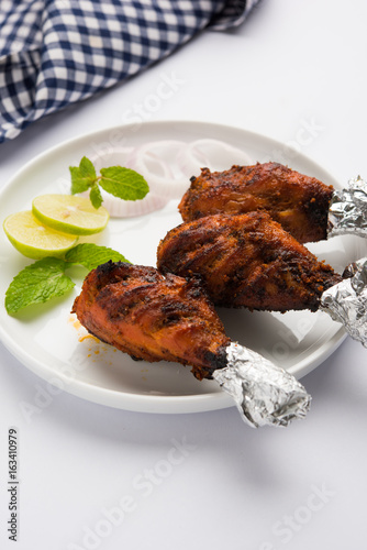 Chicken Tangri kabab or kebab - three Chicken leg pieces marinated with red sauce then grilled and served with salad. It can be served with green chutney photo