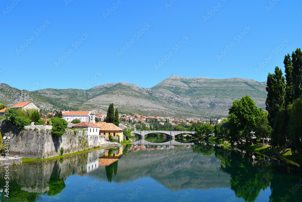 Reflections of the Kameni Most bridge and buildings in the Trebišnjica River of Trebinje, Bosnia Herzegovina