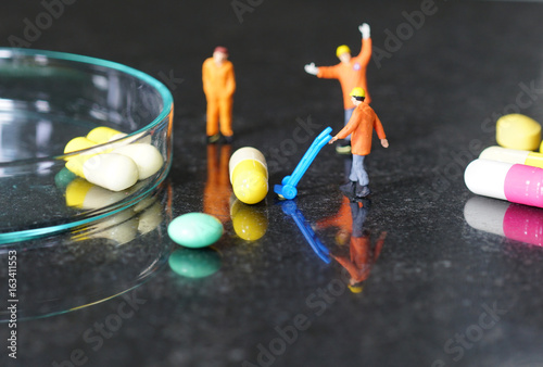 Miniature people - The worker at work with medicine pills photo
