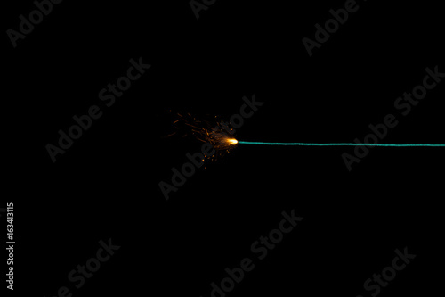 Long green fuse burning on black background isolated