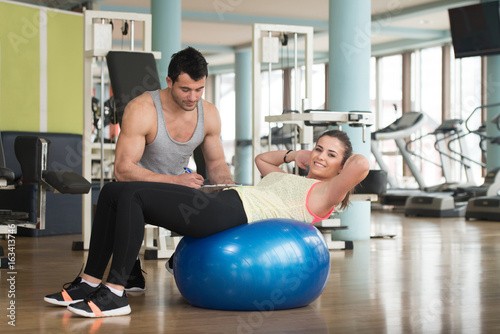 Gym Coach Helping Woman On Bosu Abs Exercise