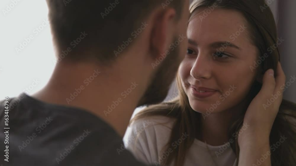 Portrait of smiling loving couple at home in the living room, looking to each others.