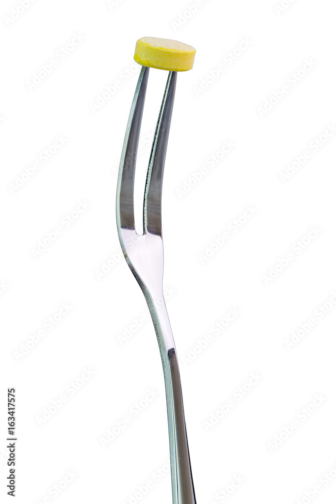 Yellow medicine tablet pierced on the fork with white background, healthcare and medical concept. Yellow medicine tablet pierced on the fork with white background, healthcare and medical concept.