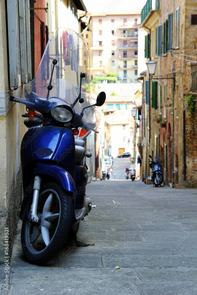 Travel to Siena, Italy. The motorcycle on the narrow street in a town.