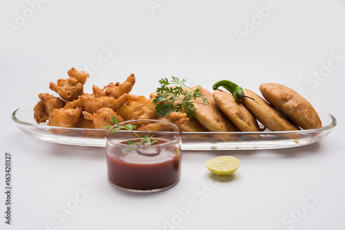 potato / aloo / batata and onion / pyaj / kanda pakora or pakode or bhajji or bajji served with tomato ketchup, green fried chilly and hot tea, Popular indian all time snack, selective focus
 photo