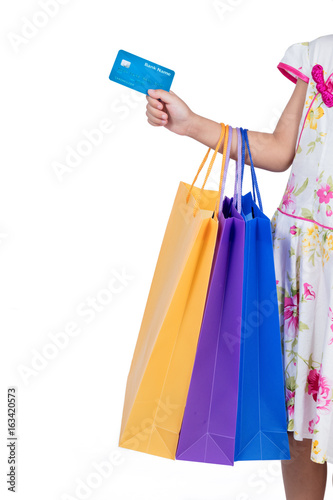 Child's hand holding credit card and colorful shopping bags
