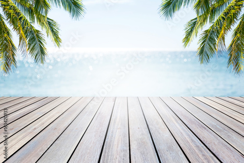 Empty wooden table and palm leaves on beach blurred background.