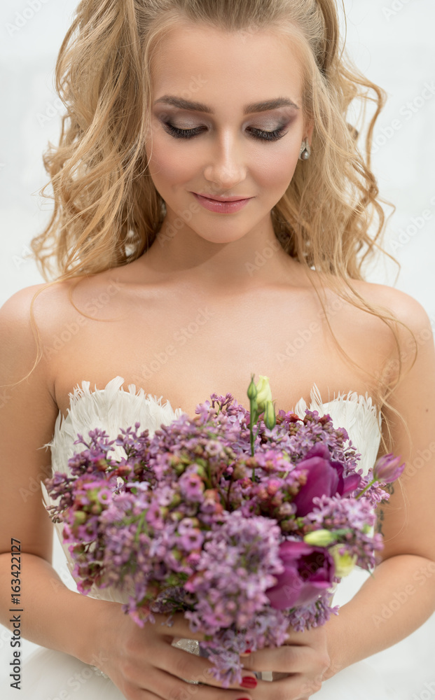 Young bride in studio admiring exquisite bouquet Young bride in studio admiring exquisite bouquet