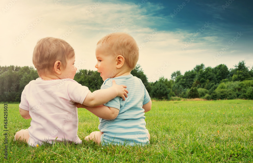 Babygirl and babyboy sitting in the grass