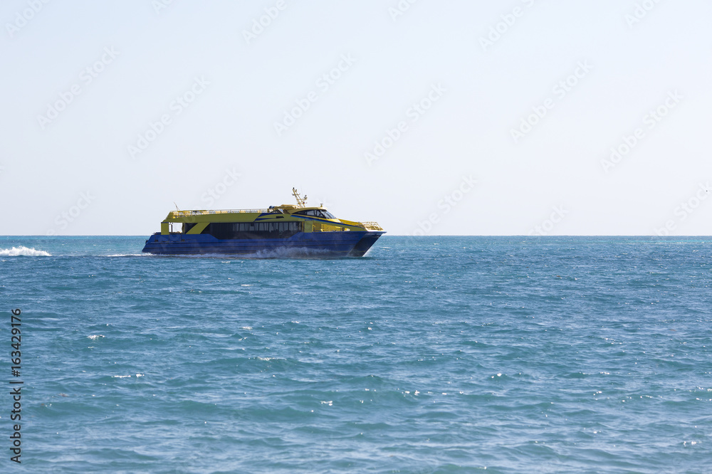 Big catamaran passenger ship going full speed ahead on the sea. Boat composed to the left.