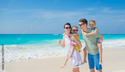 Family beach vacation. Parenta with two kids have fun on the beach