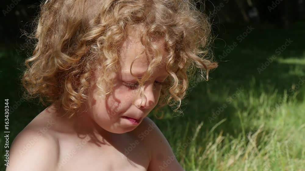 Portrait of a little blond and curly boy, slow motion
