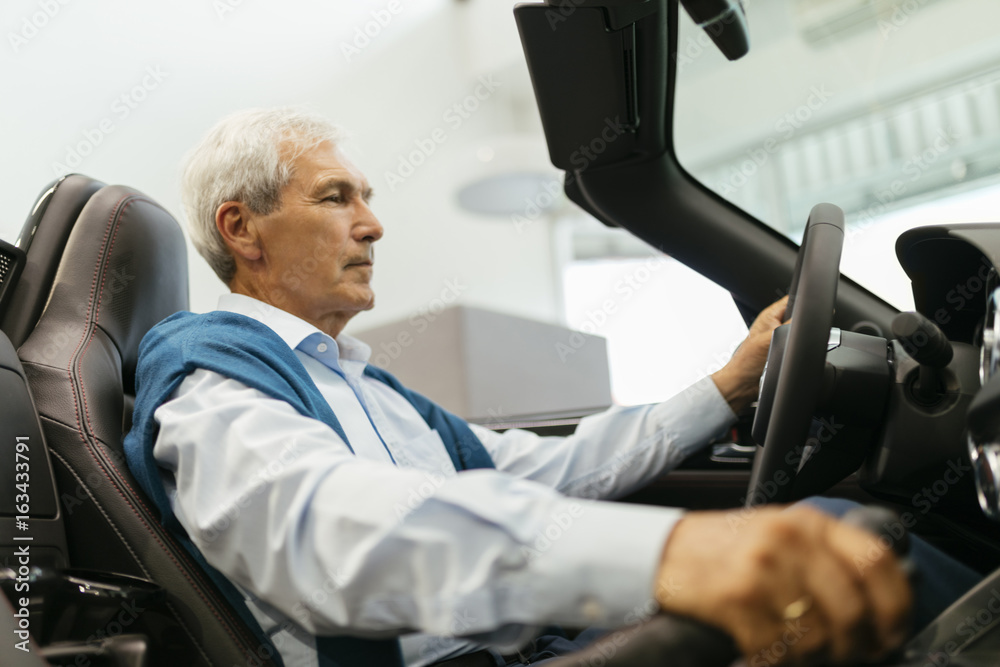 Senior man testing convertible in car dealership