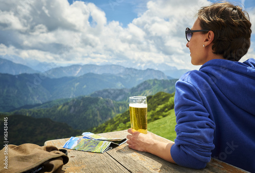 Germany, Chiemgau, hiker on Hochfelln Mountain with glass of beer looking at view photo