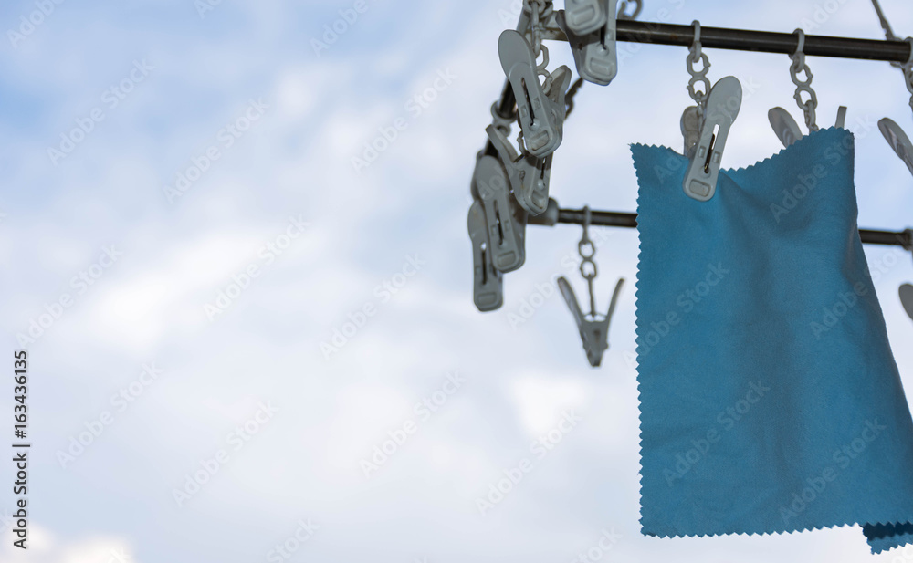 Lens cleaning cloth Hang on a white clamp after washing. Against sky and clouds background Lens cleaning cloth Hang on a white clamp after washing. Against sky and clouds background
