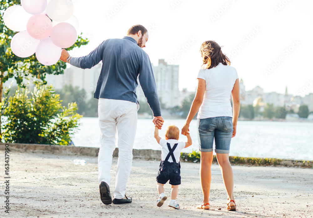 Fototapeta premium Baby's first steps with mom and dad on the street