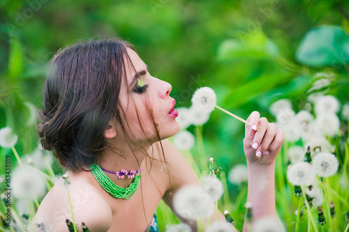 girl with fashionable makeup and beads in green leaves