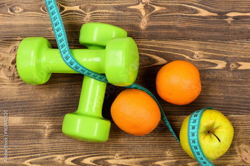 weight dumbbells with measuring tape, apple, orange, diet concept