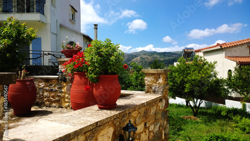 The decoration on Greek street - large bright clay flower pots and geraniums in it. © kroshanosha