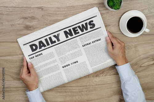 Hand is holding mockup newspapers and coffee cup.