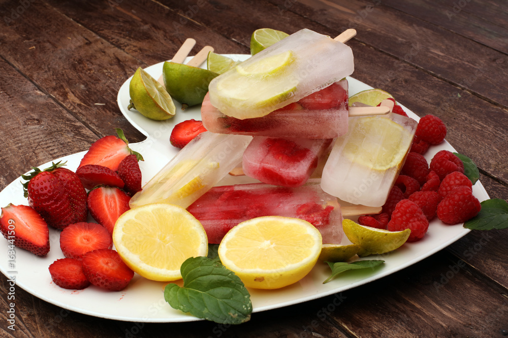 Healthy raspberry, lemon, lime, strawberry popsicles with fresh slices on wooden background Healthy raspberry, lemon, lime, strawberry popsicles with fresh slices on wooden background