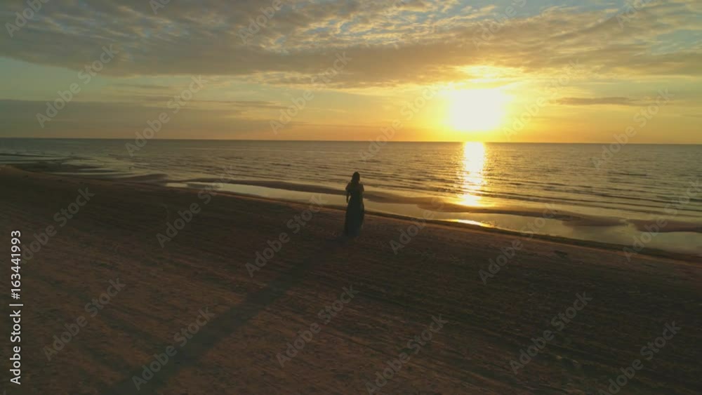 Woman enjoying a sunset on a beach