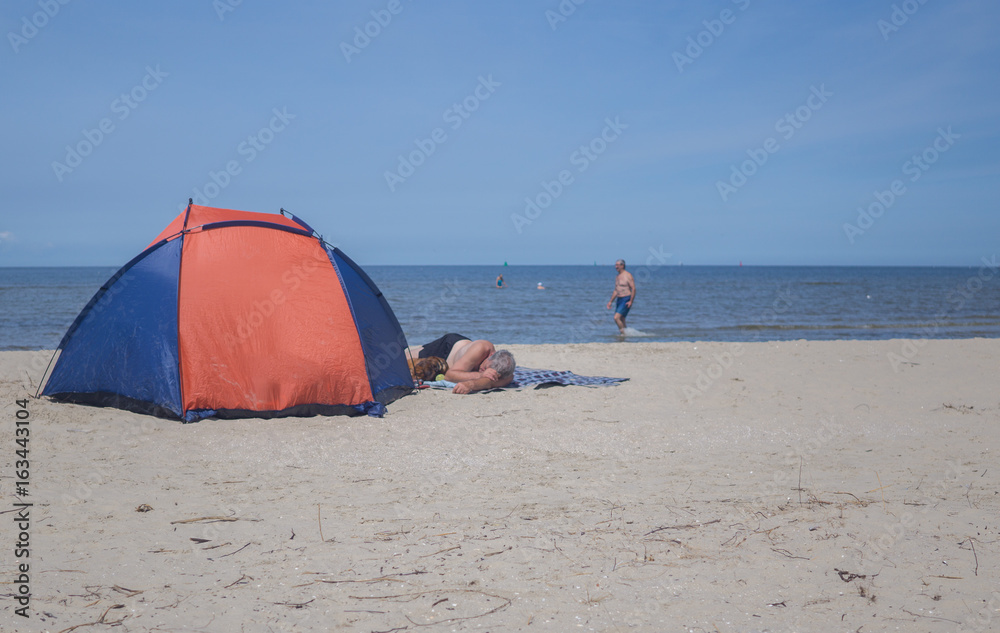 a man sleeps on the beach on the hot day in summer