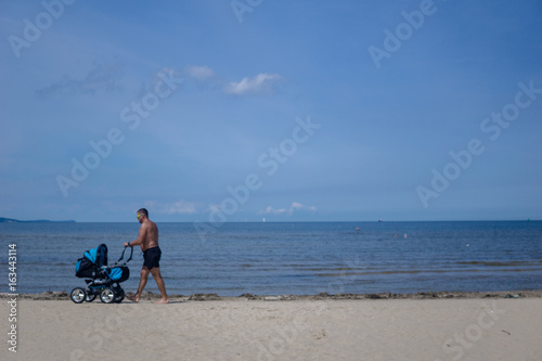 a man walks with his baby on the beach