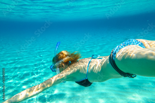 Female apnea bikini swims in crystal trapical sea. Underwater scene of a woman snorkeling and doing free diving. Watersport activity in summer vacations. Tropical destination and leisure concept.