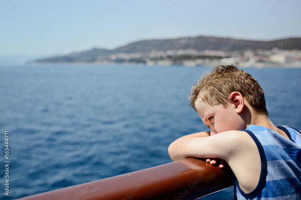 Fototapeta premium Sad thoughtful little boy looking at the sea