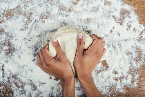 Tableau sur toile Cropped shot of hands kneading dough on wooden table top