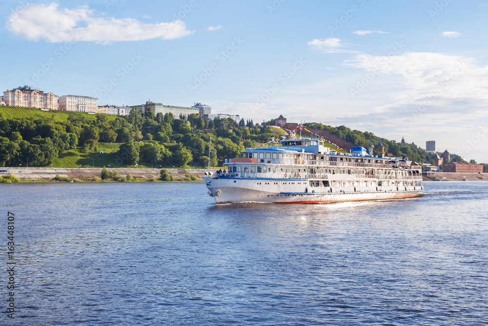Three-deck river boat in the rays of the evening sun goes along the banks of the Volga near Nizhny Novgorod