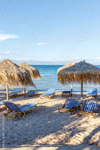 Corfu island beachside with chairs and umbrellas. Greece, sunset view