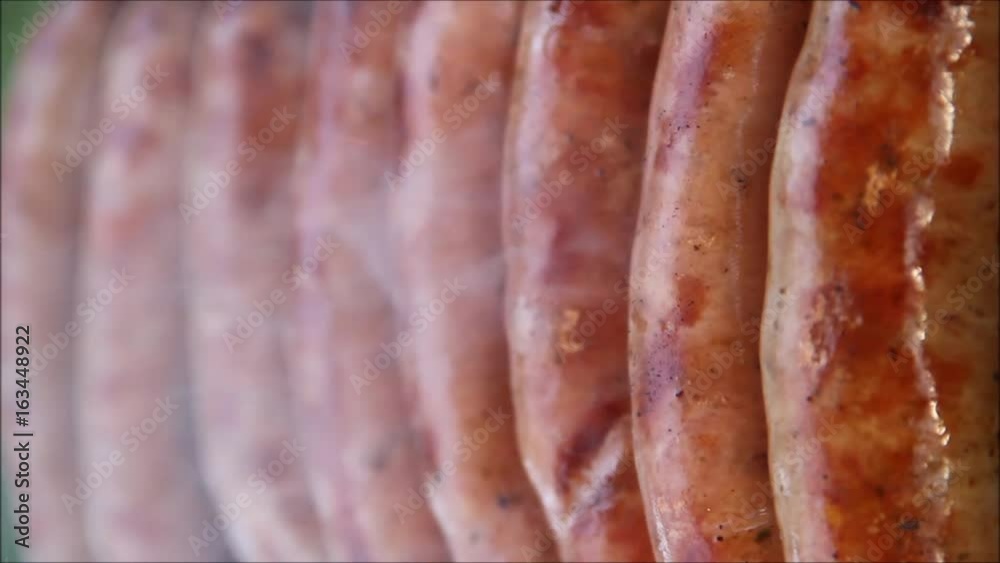 Juicy sausages rotated on grill by hand Juicy sausages rotated on grill by hand