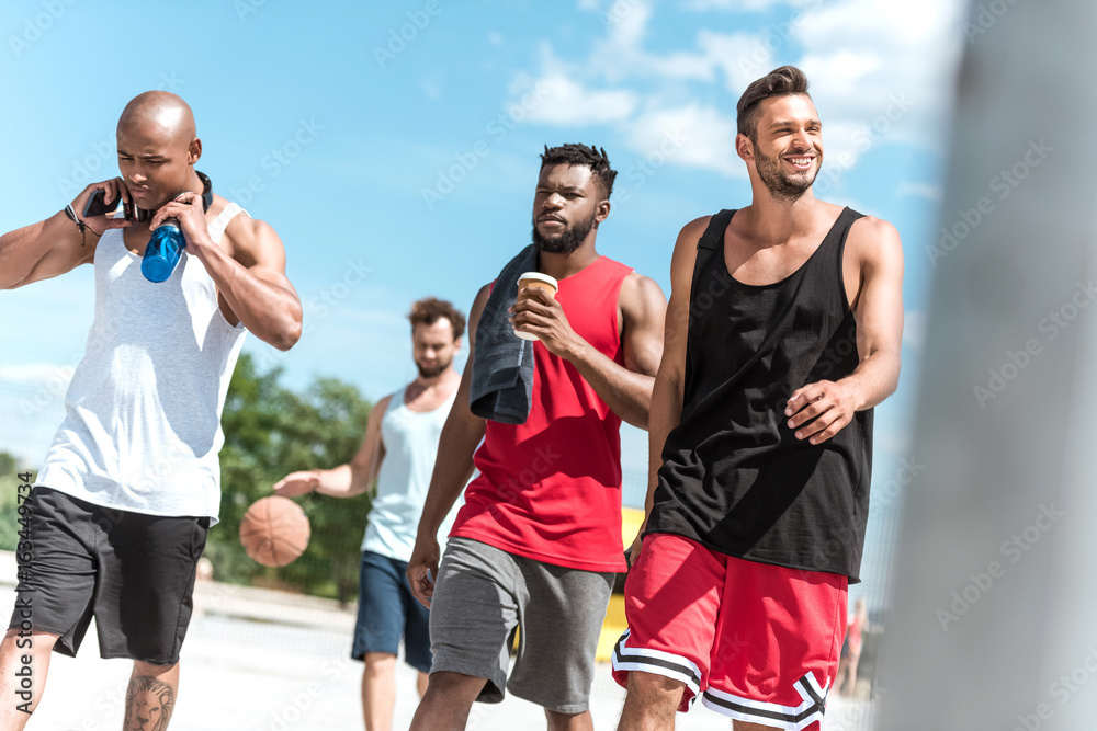 multiethnic group of athletic basketball players walking on court