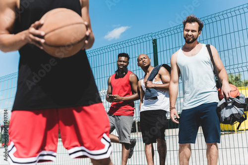 Fototapeta Naklejka Na Ścianę i Meble -  group of young multicultural men playing basketball on court