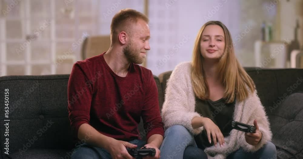 Young couple playing video games at home and making high five Young couple playing video games at home and making high five