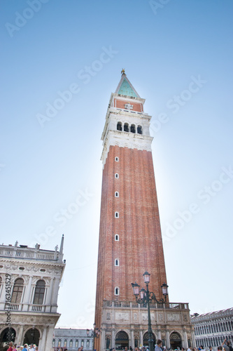 Saint Mark bell tower in the center of Venice with golden angel statue at the top and beautiful clouds © Jopstock