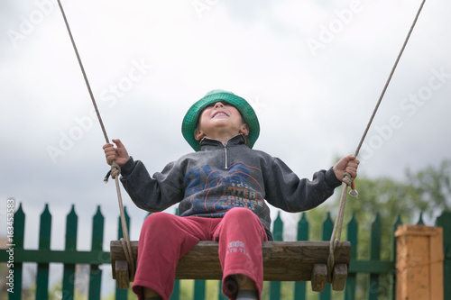 Happy boy is riding on a swing.