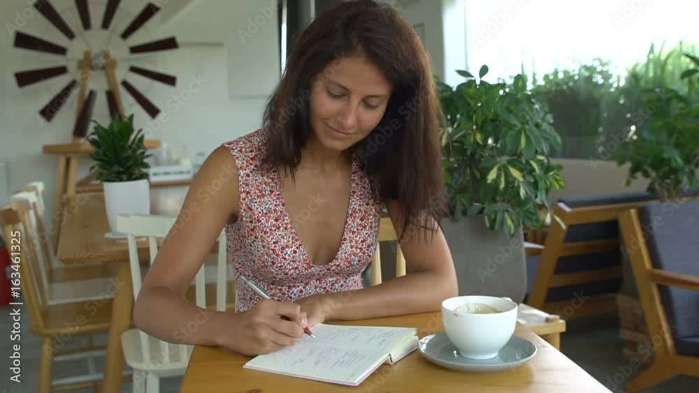Female college student writing in notepad with pen Female college student writing in notepad with pen