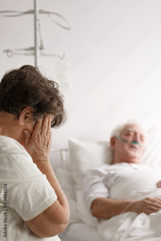 Obraz premium Woman crying next to her sick husband