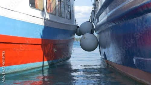 Large ships fender beetween boats in the harbor. photo